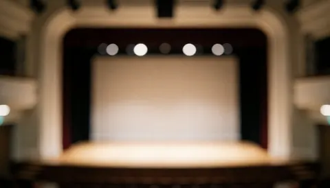 Scène de théâtre avec proscenium et lumières, fond flou pour textes, idéal pour ateliers de théâtre.