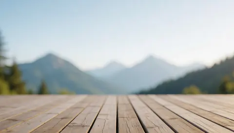 Terrasse en bois offrant une vue sur des montagnes floues en arrière-plan, idéale pour des textes ou des annonces liées aux refuges de montagne.
