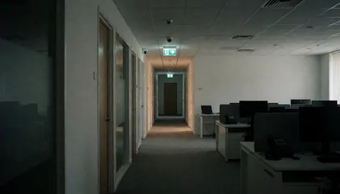 Couloir de bureau moderne vide avec lumières d'urgence et caméras de sécurité, idéal pour fond de texte sur la sécurité.