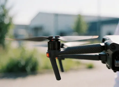 Vue rapprochée des hélices d'un drone en rotation dans un parc industriel, illustrant la technologie de la photographie aérienne.