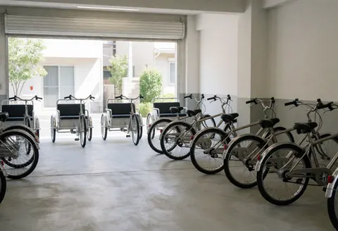 Des tricycles et vélos de livraison prêts au service dans un garage moderne avec sol en béton poli et murs blancs, idéal pour une entreprise de transport.