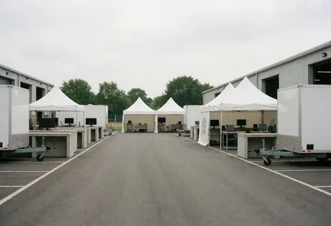Patio industriel vide avec des terrains blancs, des tables de travail et des moniteurs, prêt pour les opérations.