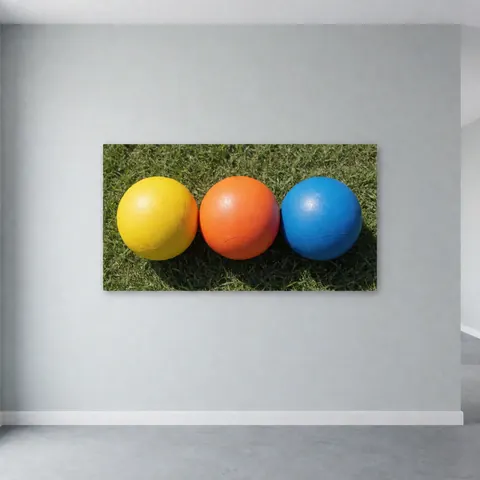 Trois ballons de football d'entraînement de couleur jaune, orange et bleu posés sur une pelouse verte, utilisés pour le sport et l'entraînement.