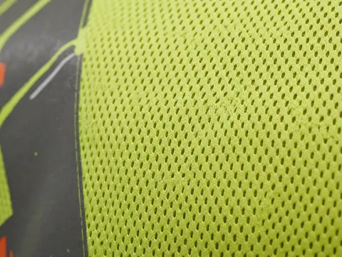 Gros plan sur un tissu de sécurité jaune néon à maille avec un motif imprimé sur le bord, illustrant la qualité du produit.