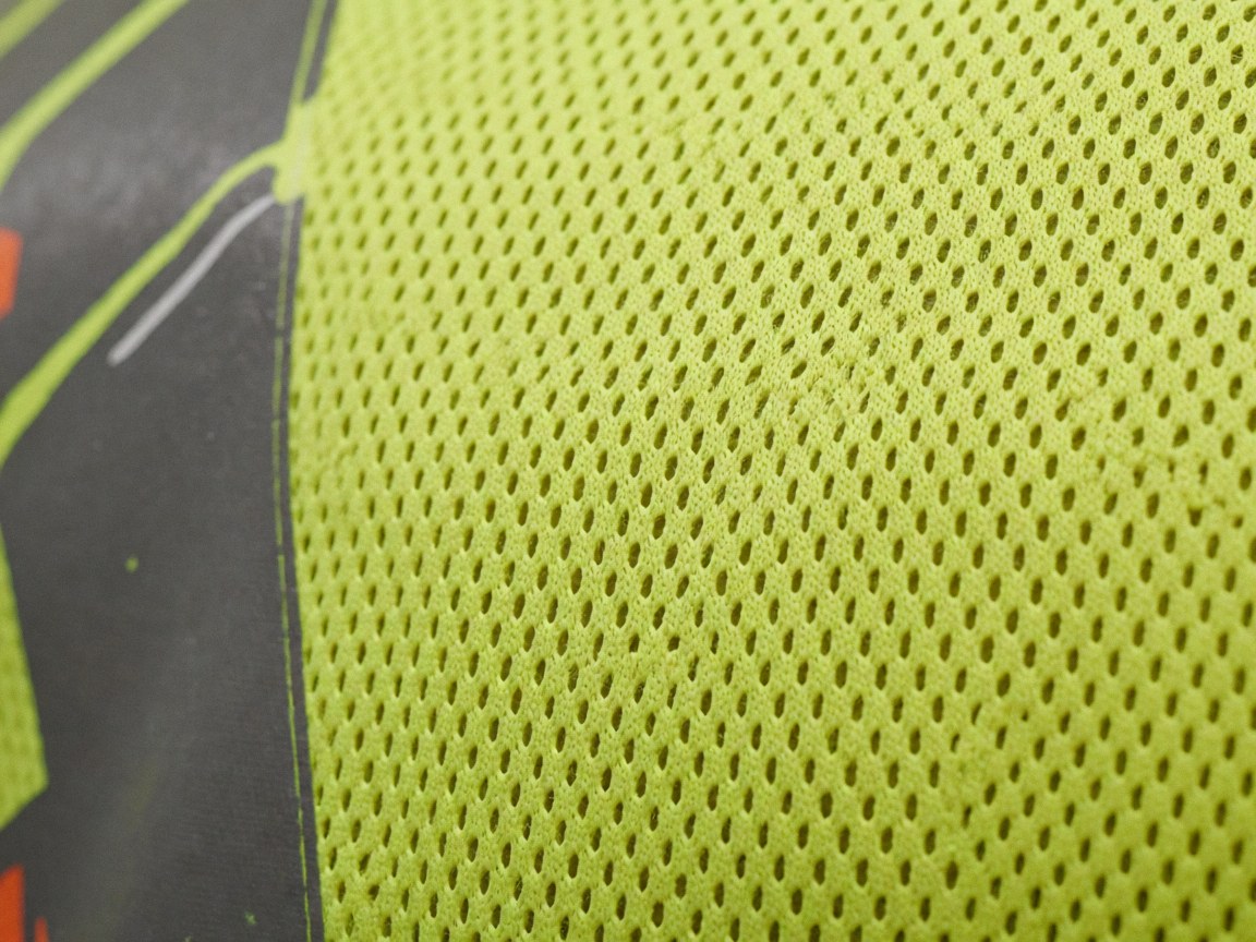 Gros plan sur un tissu de sécurité jaune néon à maille avec un motif imprimé sur le bord, illustrant la qualité du produit.