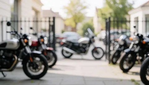 Vue de moteurs de motos stationnés dans un parking avec des clôtures métalliques et un sol en béton, offrant un fond neutre et calme pour du texte commercial.
