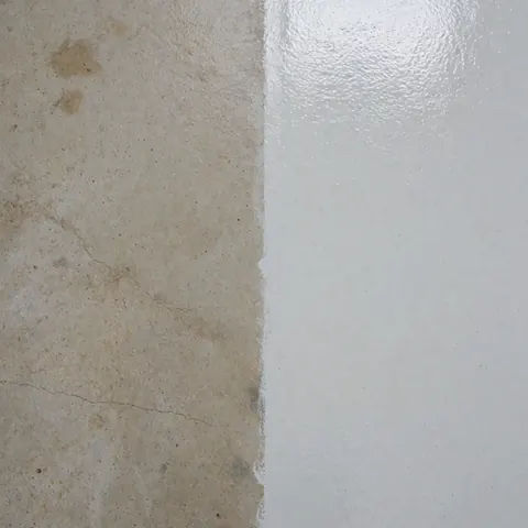 Détail d'un mur en béton montrant une zone sale à côté d'une zone propre, illustrant le résultat d'un service de nettoyage industriel professionnel.