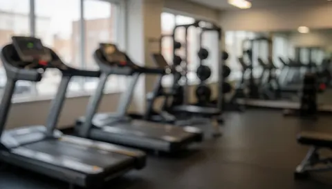 Fond de salle de sport avec tapis et haltères, idéal pour texte, ambiance chaleureuse et professionnelle.