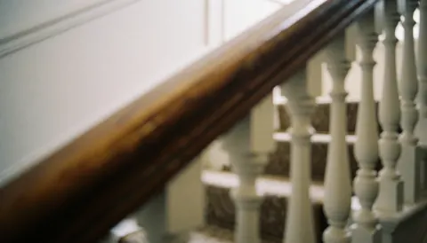 Fond d'escalier avec rampe en bois poli et balustrades blanches, idéal pour des textes sur la restauration de meubles dans des intérieurs chaleureux.