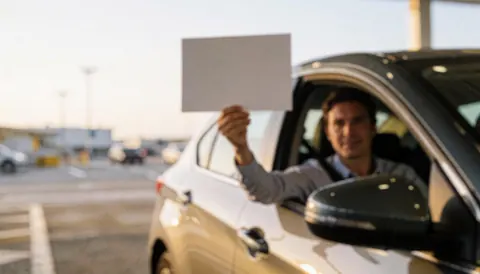 Chauffeur de taxi tenant une pancarte dans un aéroport, avec un arrière-plan flou idéal pour ajouter du texte.