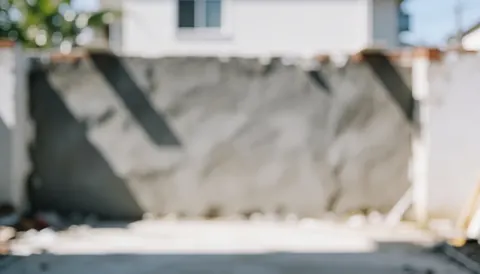 Fond de chantier avec mur gris texturé et ombres douces, idéal pour textes commerciaux sur les finitions.