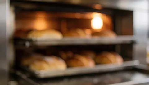 Fond de four industriel avec des pains en cours de cuisson, idéal pour des textes liés à la boulangerie.