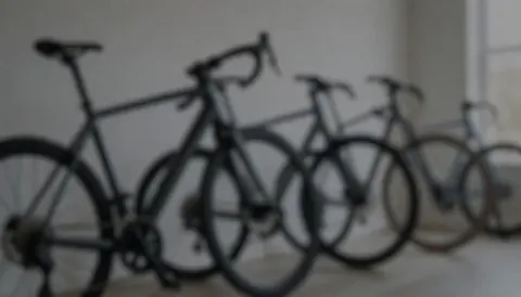Arriere-plan neutre d'un atelier de reparation de cycles avec des vélos alignés, eclairage doux et couleurs sobres ideales pour ajouter du texte.