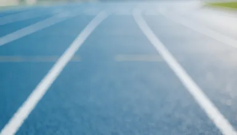 Fond de piste d'athlétisme synthétique bleue avec des marques blanches, idéal pour les textes des entraîneurs d'athlétisme.