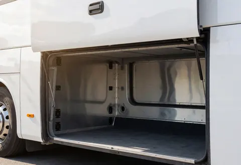 Compartiment de chargement vide et propre d'un autocar touristique, avec des parois métalliques et des points d'ancrage visibles, idéal pour le transport de bagages.