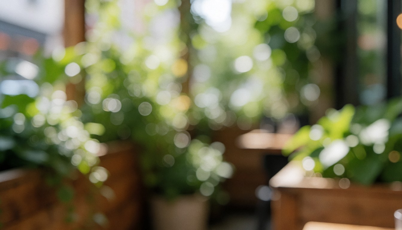 Arrière-plan flou d'une terrasse de café avec des plantes vertes et des structures en bois sous une lumière douce, idéal pour ajouter du texte.