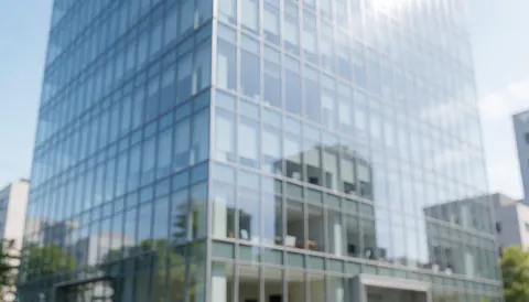 Façade d'un immeuble de bureaux moderne avec des vitres réfléchissantes et une structure métallique, idéale comme arrière-plan pour des textes commerciaux.