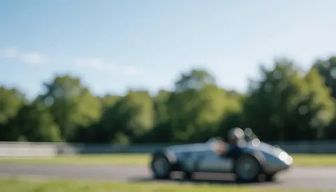 Voiture de course vintage sur une piste entourée d'arbres verts et d'un ciel bleu, idéale pour des textes commerciaux.