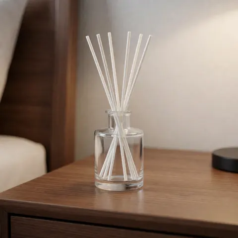 Diffuseur d'arôme avec bâtonnets blancs dans un bocal en verre posé sur une table de chevet en bois, idéal pour la décoration intérieure.
