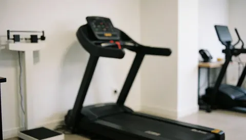 Fond de gymnase avec tapis de course et balance, idéal pour textes, ambiance professionnelle et propre.