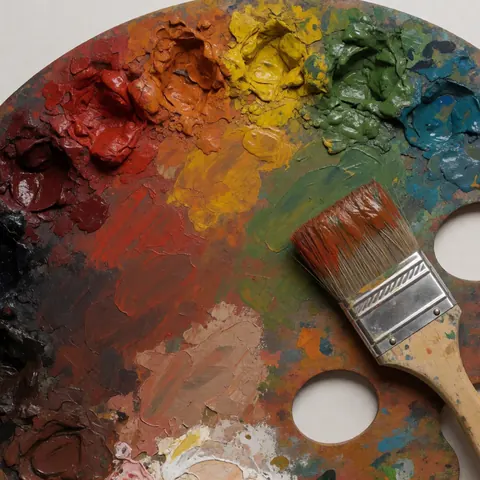 Palette de peinture contenant des pigments de couleurs terre, accompagnée d'un pinceau enduit de peinture, idéale pour la réalisation d'un mural artistique et les travaux de peinture murale.
