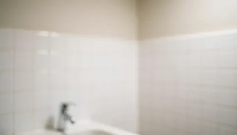 Arrière-plan de salle de bain avec murs carrelés blancs et robinet chromé, éclairage doux, idéal pour textes commerciaux