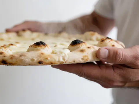 Mains tenant une pizza au fromage blanc fumante, fond blanc uni, idéal pour pizzeria.