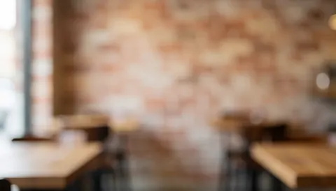 Arrière-plan chaleureux de pizzeria avec mur en briques et tables en bois floues, idéal pour ajouter du texte